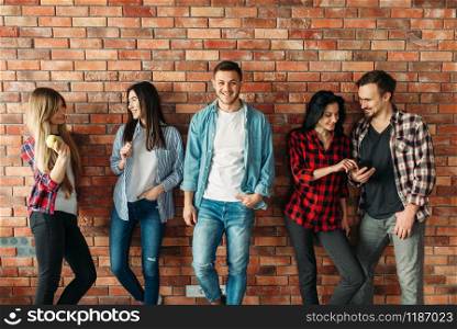 Group of university students standing at the brick wall. Highschool youth poses, lifestyle. Group of students standing at the brick wall