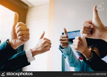 Group of unrecognizable business people pulling thumbs up in office room.