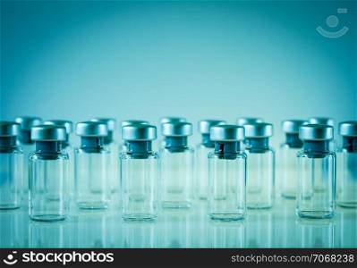 Group of vaccine glass bottles on blue background. Vaccine glass bottles on blue background