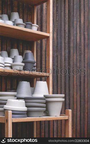 Group of vintage gray terracotta plant pots for sale on wooden shelf with wood plank wall in vertical frame