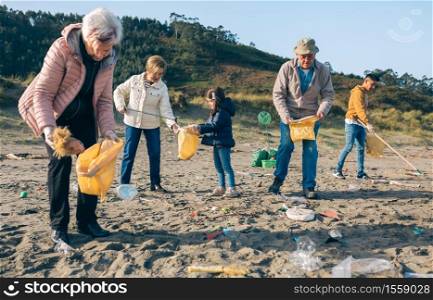 Group of volunteers picking up trash on the beach. Volunteers cleaning the beach