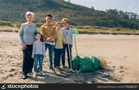 Group of volunteers posing with full garbage bags after cleaning the beach. Volunteers posing after cleaning the beach