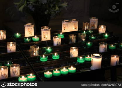 Group of white and green prayer candles in a French church