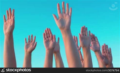 Group of white people is raising hands up in the air, clear blue sky is on the background.