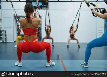 Group of women at exercise machines in gym, back view. People on fitness workout in sport club, athletic girls in sportswear on training indoors. Group of women at exercise machines in gym