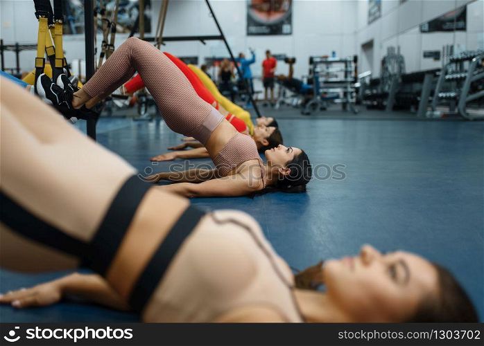 Group of women doing press exercise in gym. People on fitness workout in sport club, athletic girls in sportswear on training indoors. Group of women doing press exercise in gym