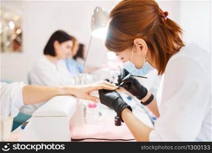 Group of women relax on manicure procedure in beauty salon. Professional beautician and female customers, nail care in spa studio, fingernail treatment. Group of women on manicure procedure, beauty salon