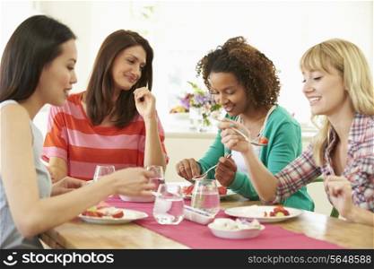Group Of Women Sitting Around Table Eating Dessert