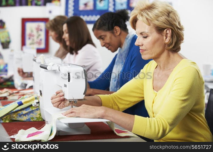 Group Of Women Using Electric Sewing Machines In class