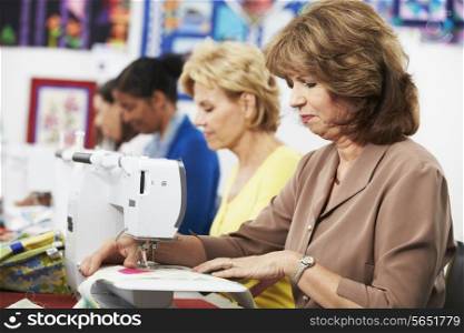 Group Of Women Using Electric Sewing Machines In class