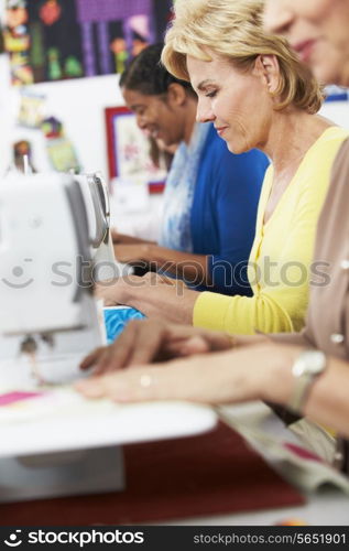 Group Of Women Using Electric Sewing Machines In class