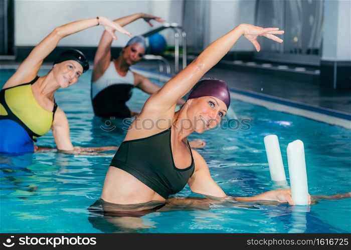 Group of Women with Female Instructor, Water Aerobics Class.. Aqua Fitness in Water Sport Centre.