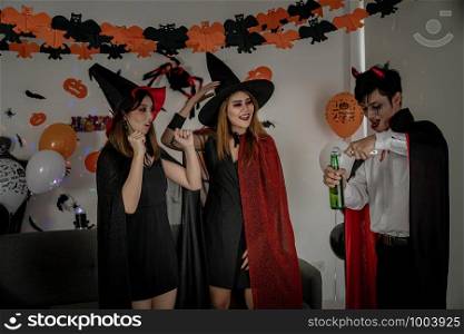 Group of young adult and teenager people celebrating a Halloween party carnival Festival in Halloween costumes drinking alcohol beer and dancing.