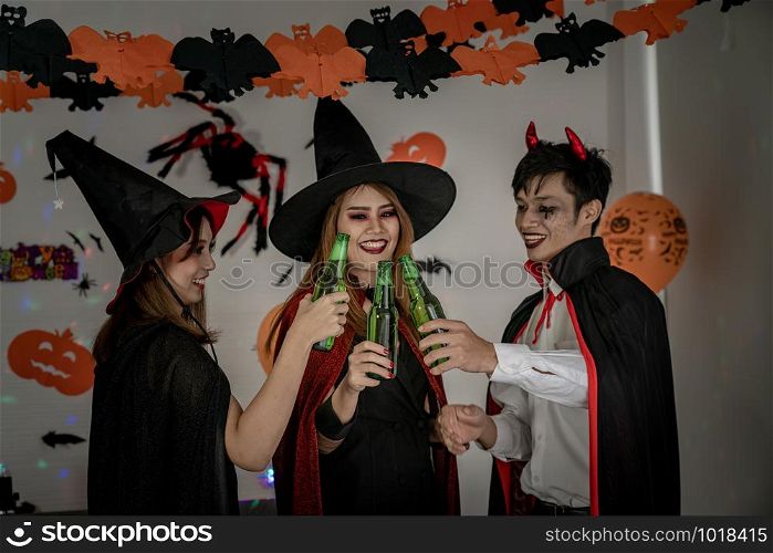 Group of young adult and teenager people celebrating a Halloween party carnival Festival in Halloween costumes drinking alcohol beer - Selective focus at beer bottless