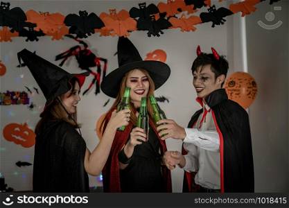Group of young adult and teenager people celebrating a Halloween party carnival Festival in Halloween costumes drinking alcohol beer - Selective focus at beer bottless