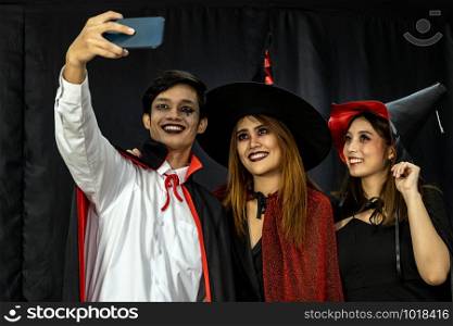 Group of young adult and teenager people celebrating a Halloween party carnival Festival in Halloween costumes take selfie photographing.