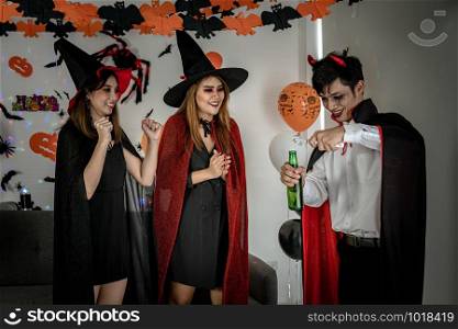 Group of young adult and teenager people celebrating a Halloween party carnival Festival in Halloween costumes drinking alcohol beer and dancing.