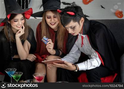 Group of young adult and teenager people celebrating a Halloween party carnival Festival in Halloween costumes and making online shopping with tablet and credit card