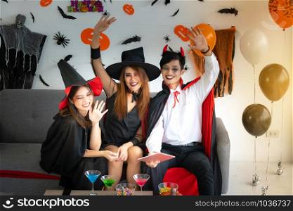 Group of young adult and teenager people celebrating a Halloween party carnival Festival in Halloween costumes with food and drink on table.
