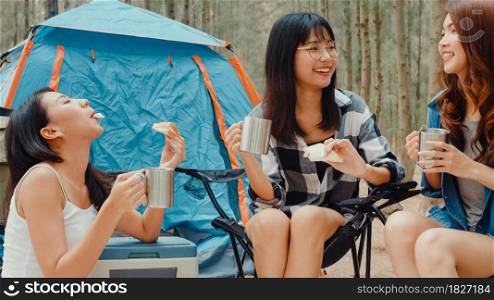 Group of young asia camper friends sitting in chairs by tent in forest. Teenager girl traveler relax and talk on a summer day at campsite. Outdoor activity, adventure travel or holiday vacation.