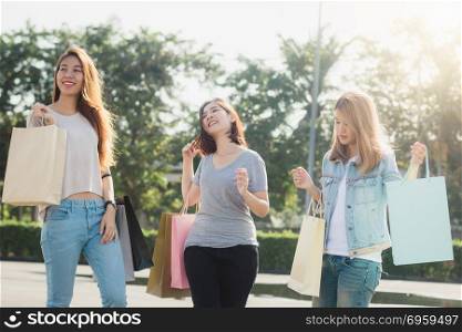 Group of young Asian Woman shopping in an outdoor market with sh. Group of young Asian Woman shopping in an outdoor market with shopping bags in their hands. Young women show what they got in shopping bag under warm sunlight. Group outdoor shopping concept.