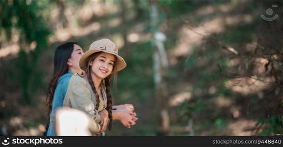 group of young asian women standing on bamboo bridge are looking beautiful nature while camping in forest with happiness together