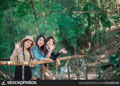 group of young asian women standing on bamboo bridge are looking beautiful nature while camping in forest with happiness together