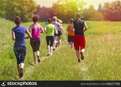 Group of young athlete running marathon outdoors in sunset