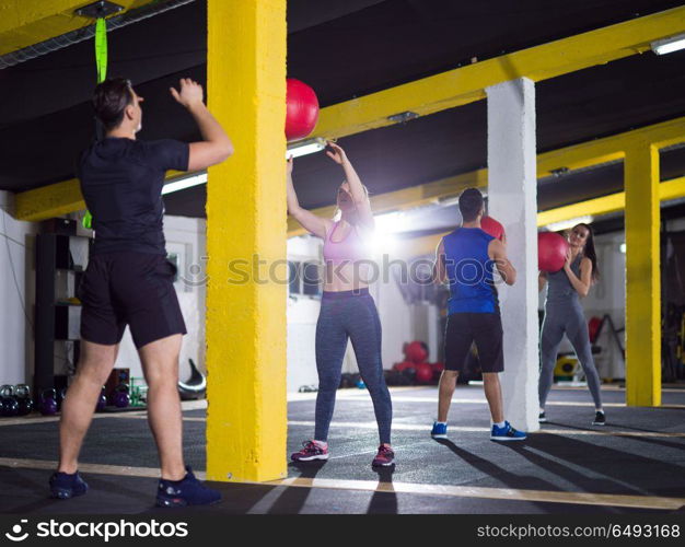 group of young athletes working out with medical ball at crossfitness gym. young athletes working out with medical ball