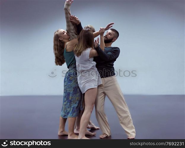 group of young athletic dance partners in black tights performing modern style ballet making acrobatic elements group of sporty ballet dancers in art performance in front of cyan background