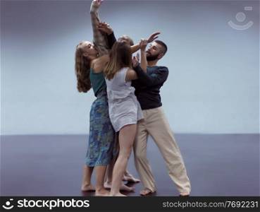 group of young athletic dance partners in black tights performing modern style ballet making acrobatic elements group of sporty ballet dancers in art performance in front of cyan background
