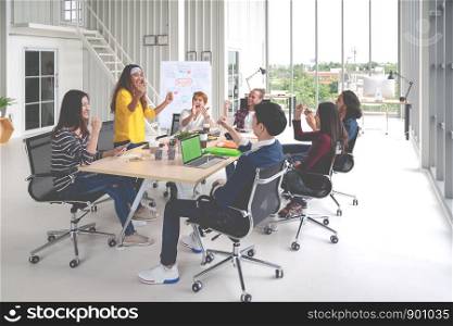 Group of young attractive asian creative design team meeting at office celebrating success or winner. Asian employee engaged together with effective and productive meeting and happy workplace concept.