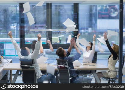 Group of young business people throwing documents and looking happy while celebrating success at their working places in startup office