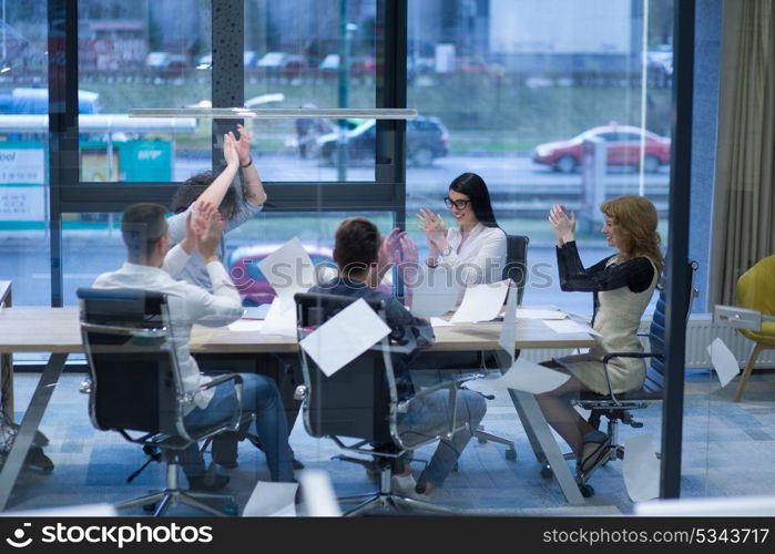 Group of young business people throwing documents and looking happy while celebrating success at their working places in startup office