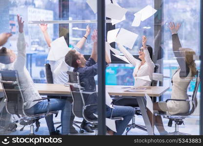 Group of young business people throwing documents and looking happy while celebrating success at their working places in startup office