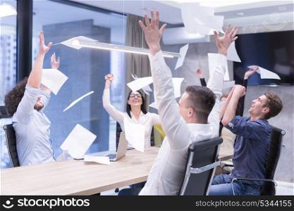 Group of young business people throwing documents and looking happy while celebrating success at their working places in startup office