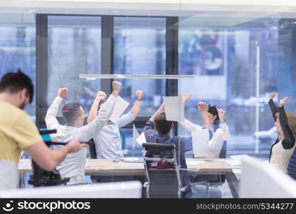 Group of young business people throwing documents and looking happy while celebrating success at their working places in startup office