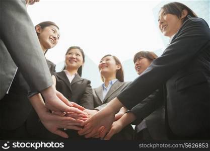 Group of young businesswoman putting hands together in a circle