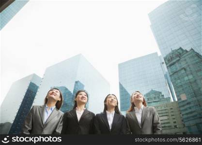 Group of young businesswomen standing in a row among skyscrapers, Beijing