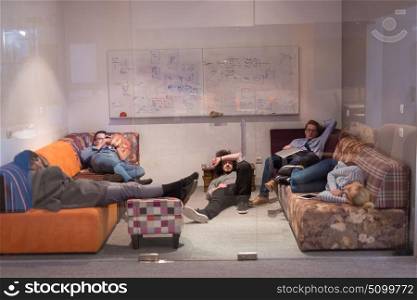 group of young casual software developer sleeping on sofa during a work break in creative startup office