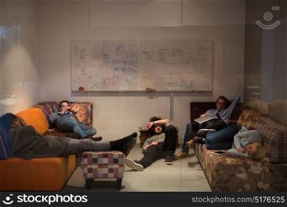 group of young casual software developer sleeping on sofa during a work break in creative startup office