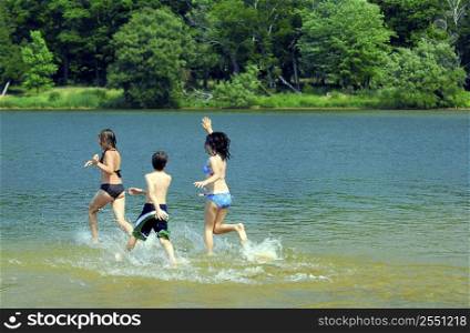 Group of young children running into water at the beach