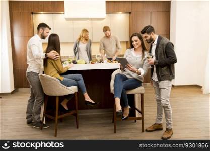 Group of young friends are in modern kitchen, talking to each other while preparing food