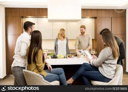 Group of young friends are in modern kitchen, talking to each other while preparing food