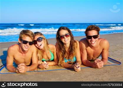 Group of young friends couples portrait in beach lying on sand at summer vacation