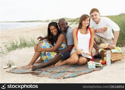 Group Of Young Friends Enjoying Picnic On Beach Together