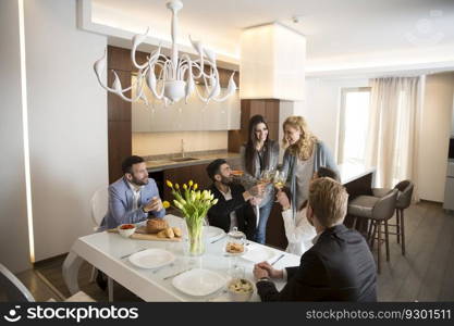 Group of young friends having dinner at home and toasting with white wine