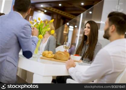 Group of young friends having dinner at home and toasting with white wine
