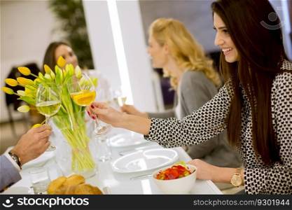 Group of young friends having dinner at home and toasting with white wine