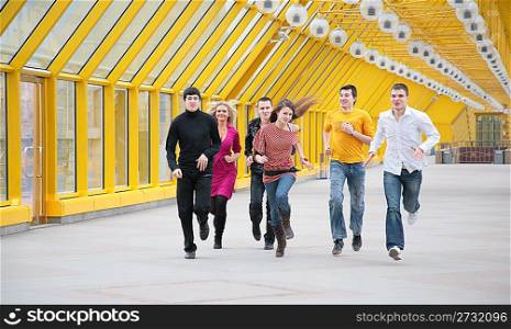 group of young friends runs on yellow footbridge